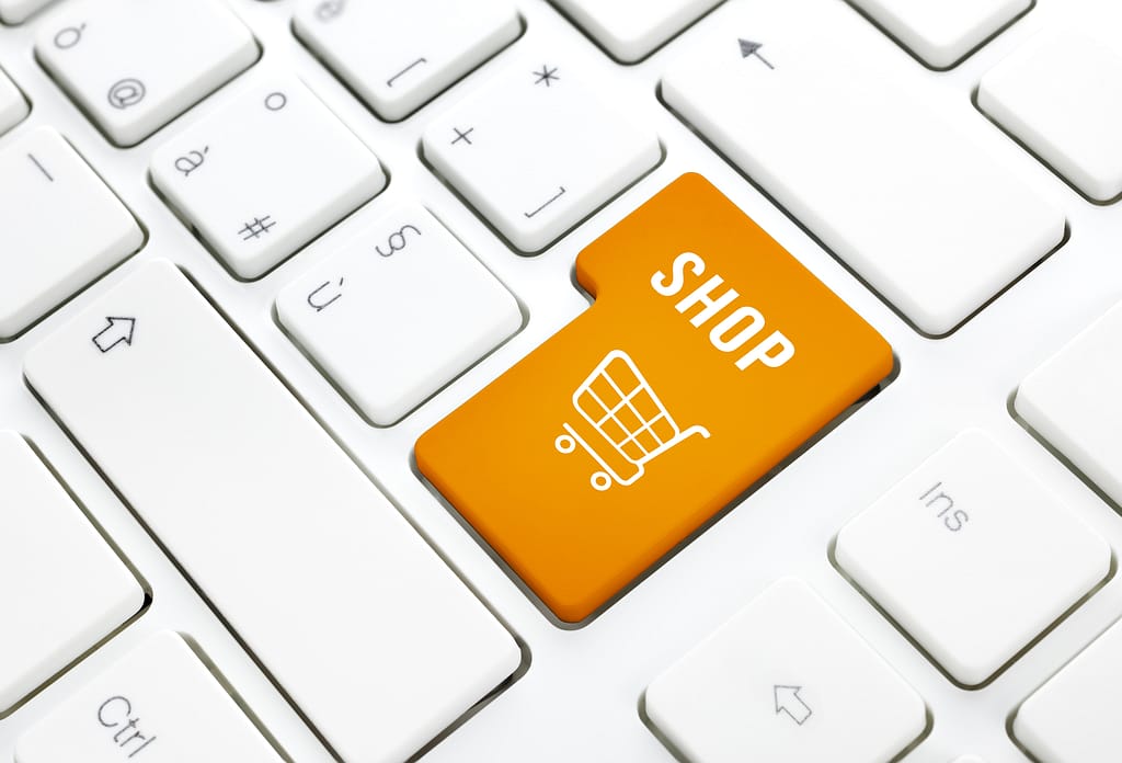 Shop business concept. Orange shopping cart button or key on white keyboard
